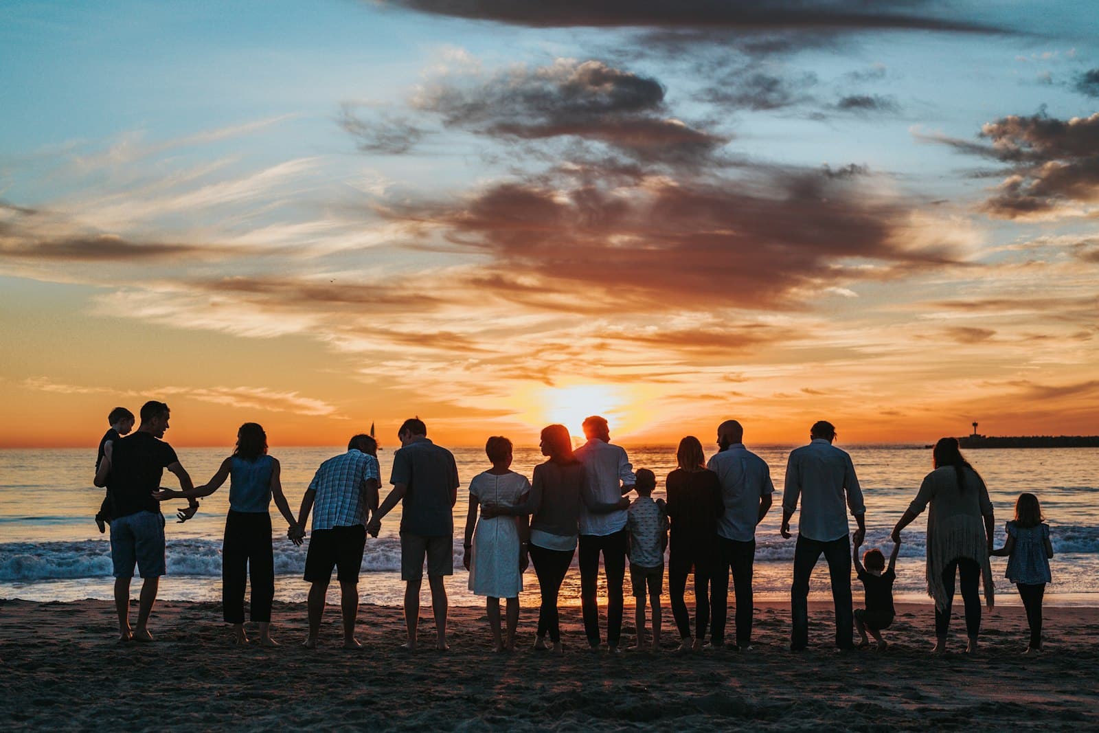 Família de mãos dadas na praia ao pôr do sol